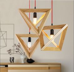 three wooden lights hanging from the ceiling in a room with white walls and wood furniture