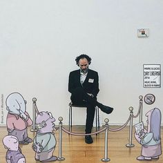 a man sitting in a chair surrounded by cartoon characters on the floor and behind him is a rope