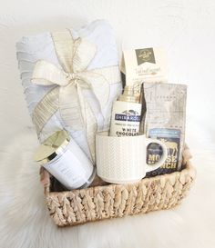 a basket filled with lots of different items on top of a white blanket next to a pillow