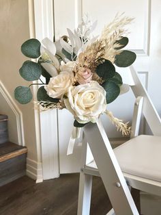 a bouquet of flowers sitting on top of a white chair next to a stair case