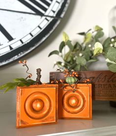 two orange wooden speakers sitting on top of a table next to a plant and clock