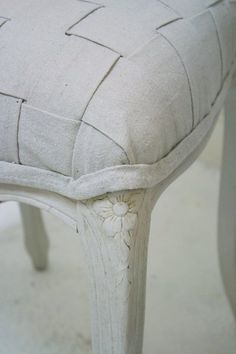 a close up of a white chair with a flower on the seat and back rest