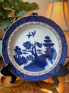 a blue and white plate sitting on top of a wooden table next to a lamp