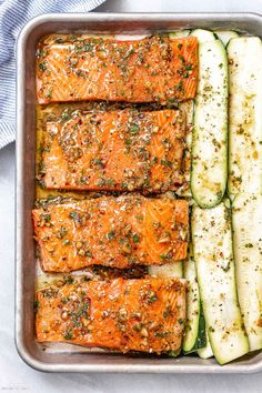 salmon and zucchini in a baking pan with seasoning on the side, ready to be cooked