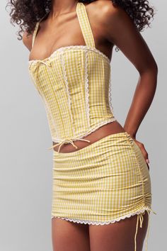 The Gingham Ruched Side-Tie Mini, features cotton construction with a concealed back zip. Trimmed by scalloped lace and featuring ruched side ties for a customizable fit. Composition: 100% Cotton Eileen is wearing a size S and is 5'9" with a 32" bust, 35" hips, and 25.5" waist Gingham Corset, Gingham Set, Coachella Fits, Yellow Corset, Gingham Outfit, Pucci Vintage, Mini Skirt Set, Lace Corset, Lovely Clothes