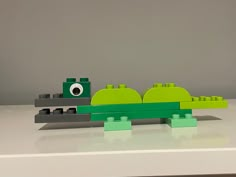 a lego toy is sitting on top of a white table and it looks like an alligator