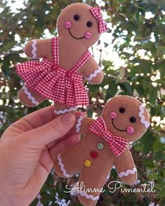 two gingerbreads with pink bows and buttons on them are being held up by someone's hand