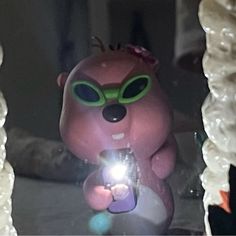 a pink bear with green eyes holding a cell phone in front of it's reflection