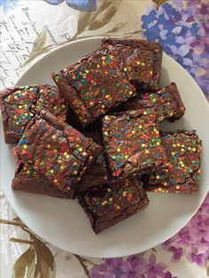 a white plate topped with brownies covered in sprinkles