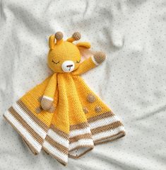 a stuffed animal is laying on top of a blanket that's made out of knitted material