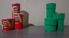 three cans of peanut butter next to each other on a table with stacks of stacked ones in the background