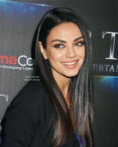 a woman with long black hair smiling at the camera