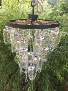 a chandelier hanging from a tree in the woods with lots of wine glasses