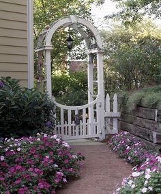 a garden with flowers and a white gate