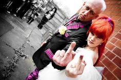 a man and woman dressed up in wedding attire pointing at the camera with their fingers