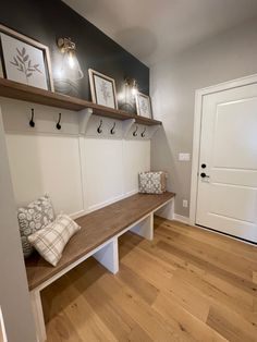 a wooden bench sitting next to a white door in a room with pictures on the wall