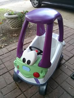 a purple and green toy car sitting on the sidewalk