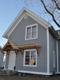 a gray house with white trim and wooden pergols on the front porch area