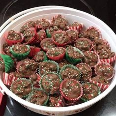 a white bowl filled with chocolate cupcakes covered in sprinkles on top of a table