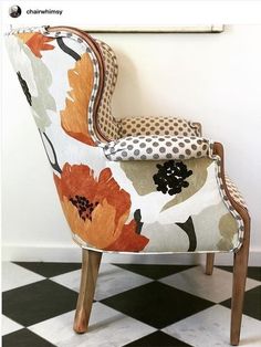 an upholstered chair sitting on top of a black and white checkered floor