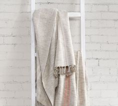 a towel hanging on the side of a white ladder next to a brick wall in front of a window