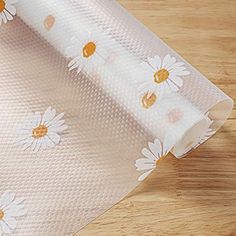 a close up of a paper with daisies on it and a wooden table in the background