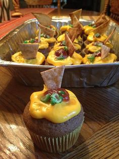 cupcakes with yellow frosting and toppings in tin pan on wooden table