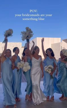 a group of women in blue dresses standing next to each other with their hands up