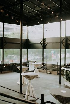 tables and chairs are set up in an empty room with lots of glass doors to the outside