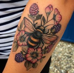 a woman's arm with a bee and flowers on it