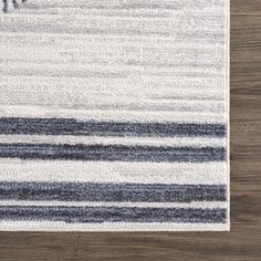 a white rug with black and grey stripes on it, next to a wooden floor