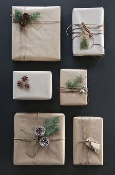 six wrapped presents with pine cones and bows on them, all tied up in twine