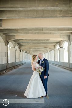 a bride and groom kissing under an overpass