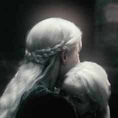 two women with white hair and braids hugging each other in front of a dark background