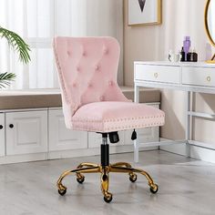 a pink office chair with gold wheels in front of a white desk and mirror on the wall