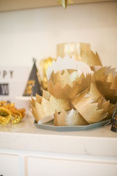 some gold decorations are sitting on a white counter top with other items in the background