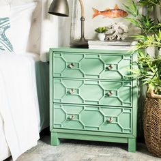 a green dresser next to a bed with plants on it and a lamp in the corner