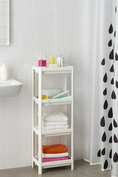 a white shelf with towels and soaps on it in front of a shower curtain