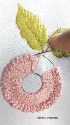 someone is stitching a leaf on a piece of fabric