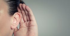 a woman is holding her ear up to hear the same sound as she holds her hand in front of her ear