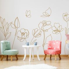 two chairs and a table in front of a wall with flowers painted on the walls