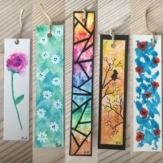 four bookmarks with flowers painted on them, hanging from twine strings and paper tags