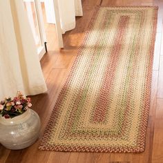 a rug on the floor next to a vase with flowers