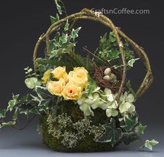 a basket filled with flowers and greenery on top of a table