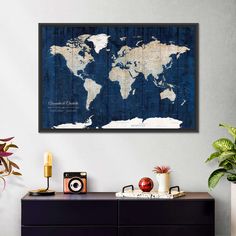 a blue and white world map hanging on the wall above a dresser with two cameras