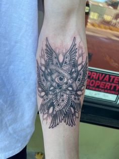 an owl tattoo on the leg of a man's left arm, which is black and grey