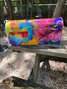 a colorful painted purse sitting on top of a wooden bench next to a park bench