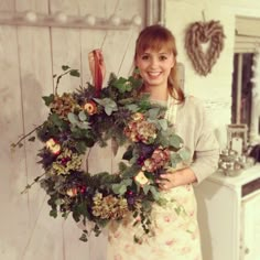 a woman is holding a wreath with flowers