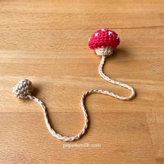 a crocheted mushroom on a wooden table with white string attached to the top