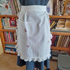 the apron is white and has pink flowers on it, with ruffles at the bottom